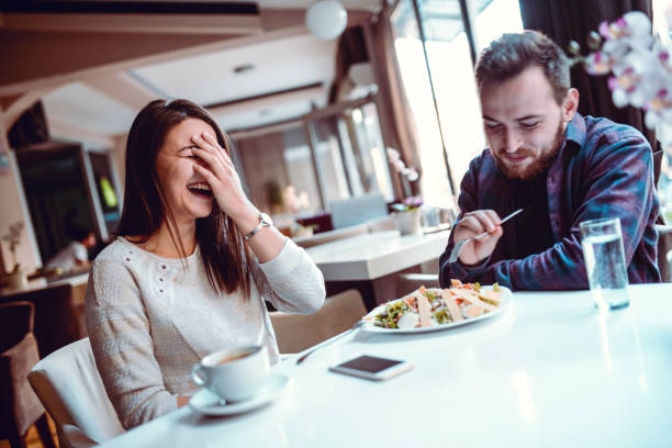 istock Cute Couple Laughing While Eating Caesar Salad In Restaurant 1159798076