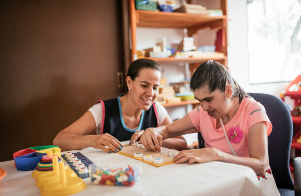 istock Hispanic teacher playing with woman with Down Syndrome 1159799353