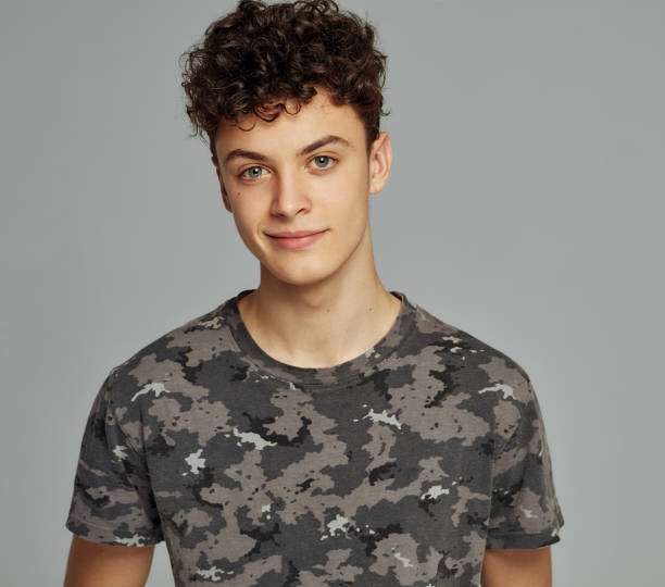 Portrait of handsome boy posing in photo studio Portrait of smiling man on gray background looking at camera teenager boy haircuts stock pictures, royalty-free photos & images
