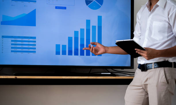 istock Speaker man talking to audience giving a lecture and holding tablet. Business presentation concept. 1159801217