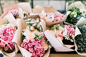 アジサイ、バラ、ピオニー、ピンクと海の緑の色で作られたテーブルの上の花屋で花の花束の多く