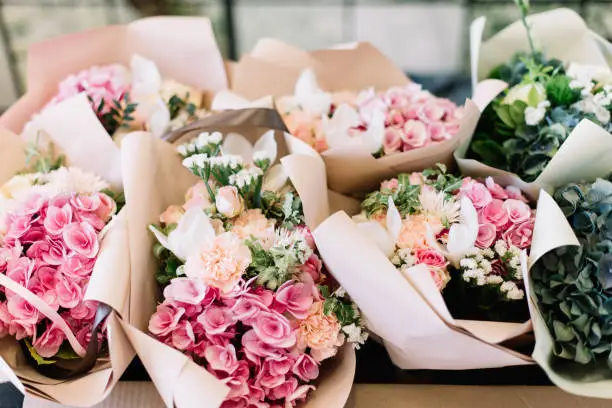 Photo of A lot of flower bouquets at the florist shop on the table made of hydrangea, roses, peonies, eustoma in pink and sea green colors