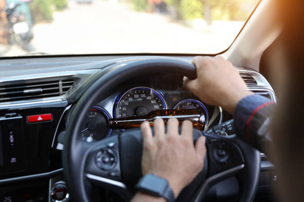istock man hands driving with alcohol bottle on mileage car dashboard 1159803177