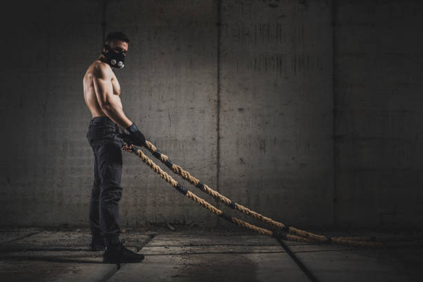 istock Muscular man doing a battle ropes workout 1159804128