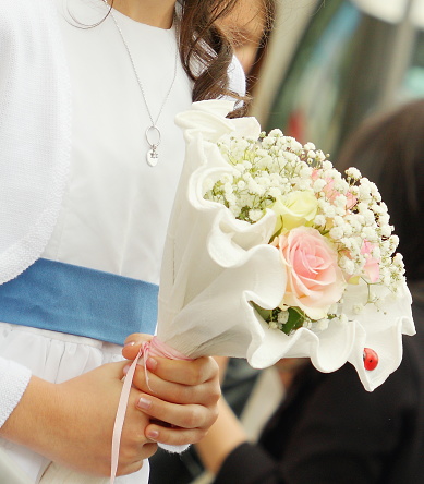 Young girl holding first communion flower bouquet in her hands