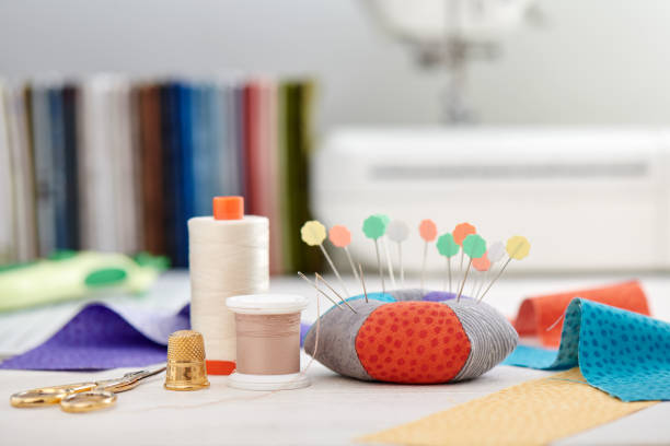 istock Pin cushion, brightly colored strips of fabric, sewing accessories  on the background of stack of fabrics and sewing machine 1159805546