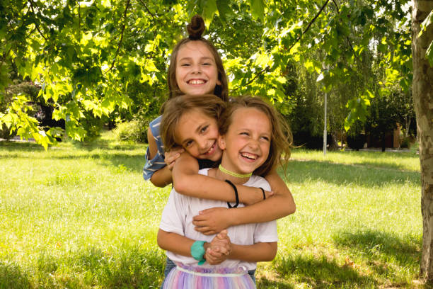 szczęśliwe siostry bawiące się w parku - child laughing blond hair three people zdjęcia i obrazy z banku zdjęć