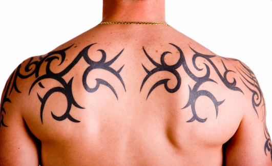 Muscular back with tribal tattoo isolated against white background