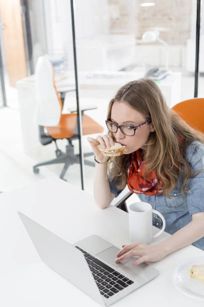 Businesswoman using touchpad of laptop while having breakfast in office