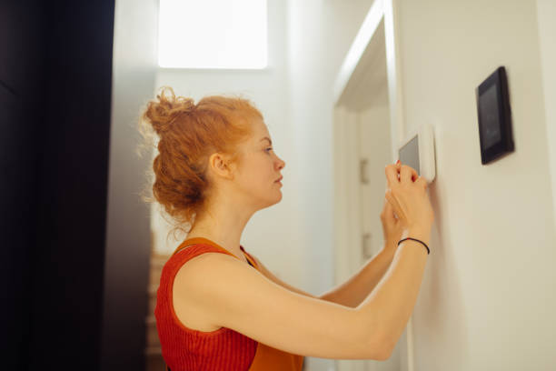 istock Serious young woman setting up the alarm system 1159816641