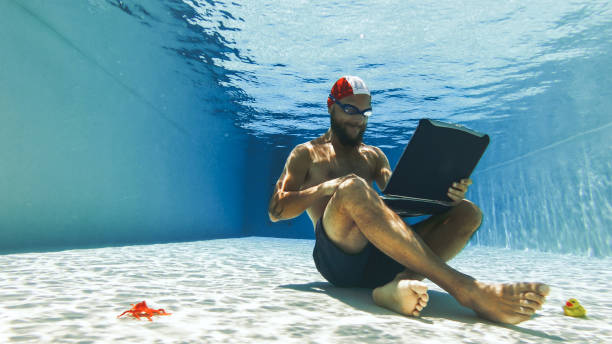 homme bourreau de travail utilisant l'ordinateur portatif sous l'eau - men naked water male photos et images de collection