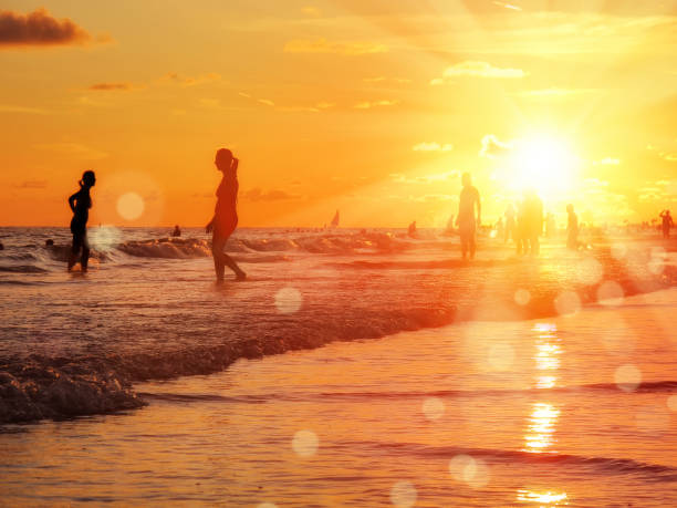 istock group of silhouetted people on public beach over orange colored sunset sky 1159827794