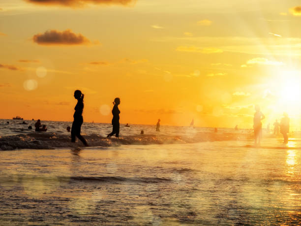 istock group of silhouetted people on public beach over orange colored sunset sky 1159828110
