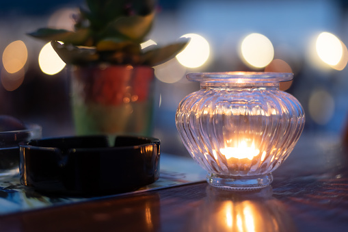 wooden table with ashtray and plant illuminated by romantic candle light