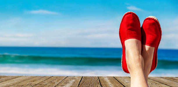 Legs with red cloth shoes in front of beach stock photo