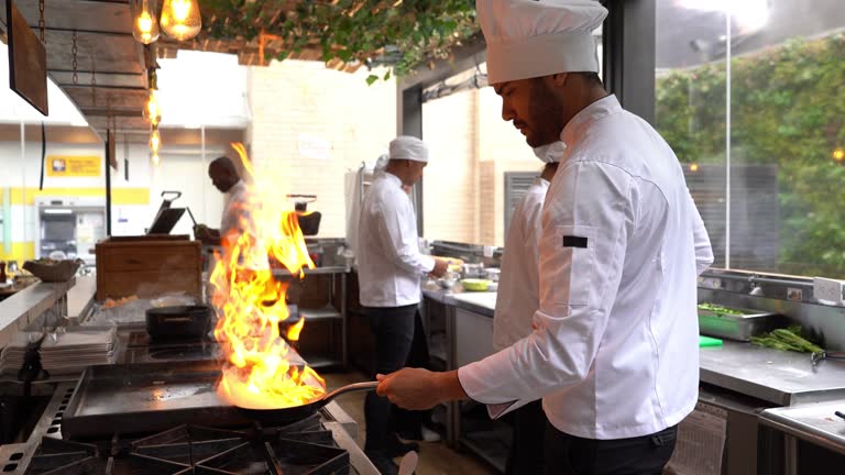 Chef cooking flambe in a pan looking focused