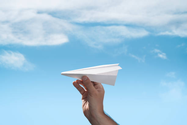 istock Men's hand launches paper origami plane 1159842847