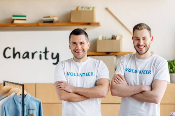 istock two handsome volunteers standing with crossed arms and looking at camera 1159843846