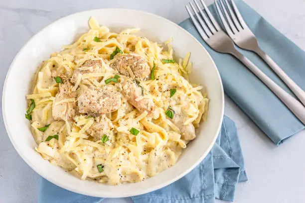 One Pot Chicken Alfredo Pasta in a Bowl Close-Up Photo. Creamy Chicken Pasta with Basil Leaves, Italian Food Photography.