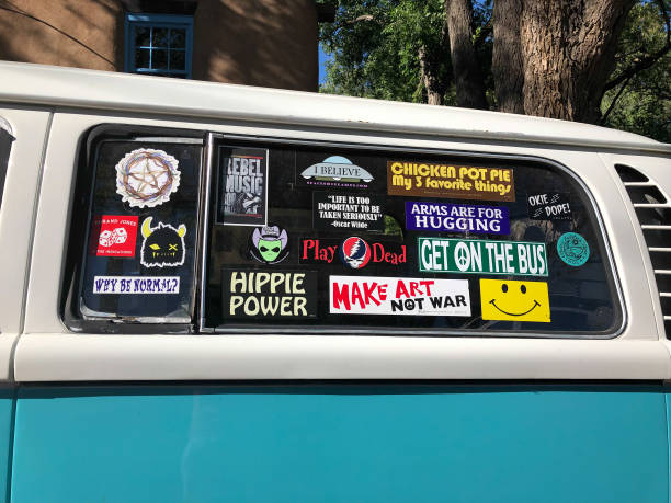 Santa Fe, NM: Vintage VW Van Covered with Bumper Stickers Santa Fe, NM: A vintage VW van window covered with bumper stickers, including peace symbols, a “Hippie Power” sticker, and a sticker reading “Make Art Not War.” hippie car stock pictures, royalty-free photos & images