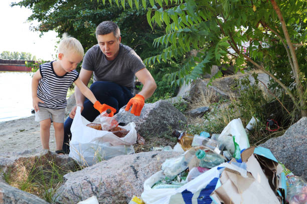 istock A small child collects trash on the beach. His dad points his finger where to throw garbage. Parents teach children cleanliness. Clean planet concept 1159847636