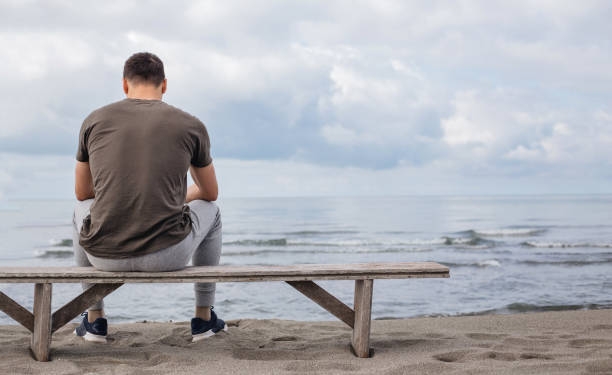istock Contemplating man watching the sea from a beach bench 1159847656