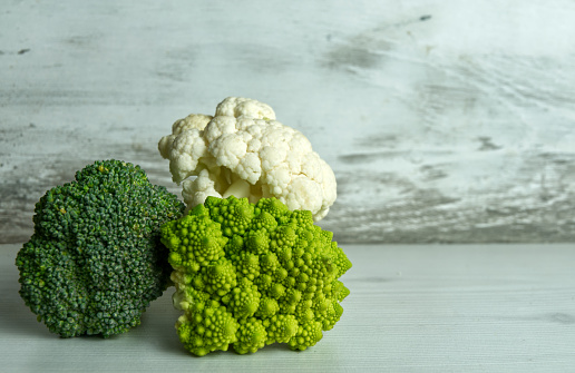 broccoli, cauliflower and romanesco cole lying on white kitchen worktop