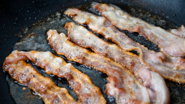 istock Slices of bacon baking on the pan 1159852664