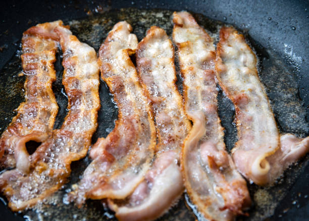 istock Slices of bacon baking on the pan 1159852665