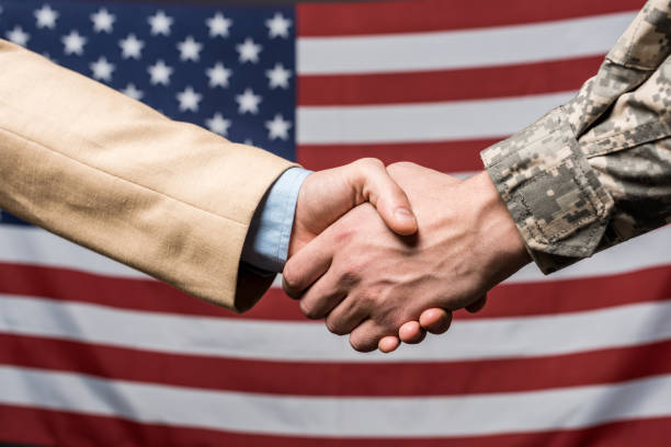 istock selective focus men shaking hands near american flag 1159857113