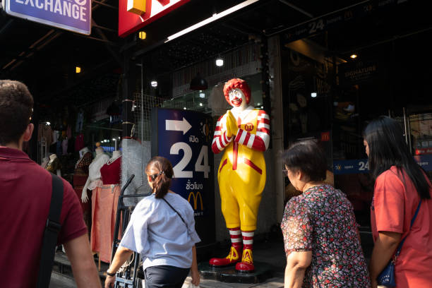 pedestres andam após o mascote do mcdonald ' s na frente do restaurante na tailândia - bangkok mcdonalds fast food restaurant asia - fotografias e filmes do acervo