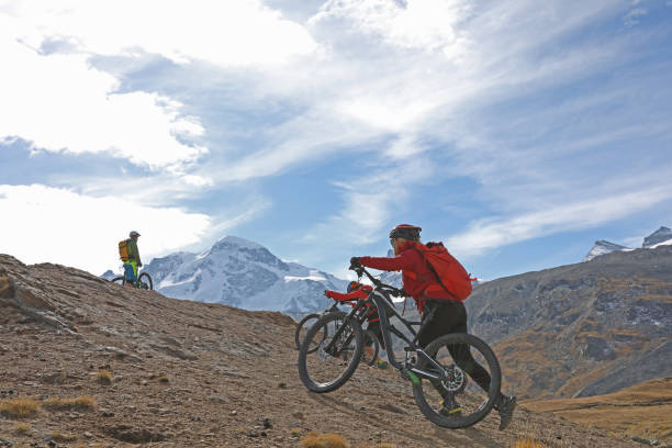 istock Mountain bikers push their bikes up an alpine slope below the Matterhorn mountain 1159859403