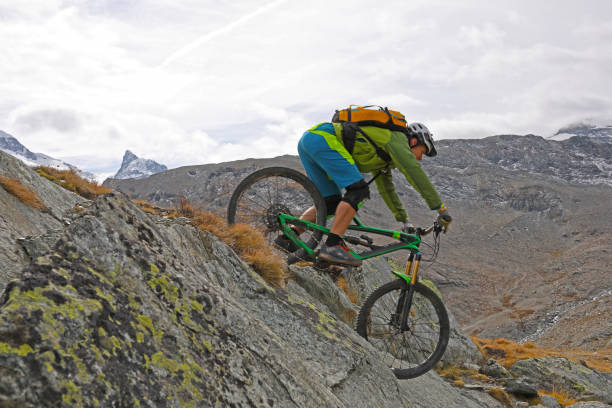 istock Mountain biker rides down rock slab below the Matterhorn mountain 1159859437
