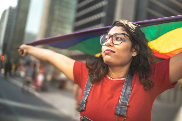 istock Young woman holding rainbow flag during pride parade 1159859495