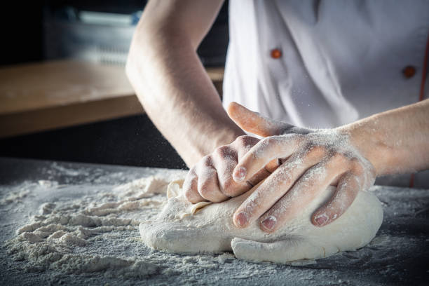 istock Chef prepares the dough with flour. Hands kneading raw dough Horizontal. Copy space. Gluten free dough for pasta, bakery or pizza. Baker workplace. Chef makes dough. Culinary, cooking, bakery concept 1159861156
