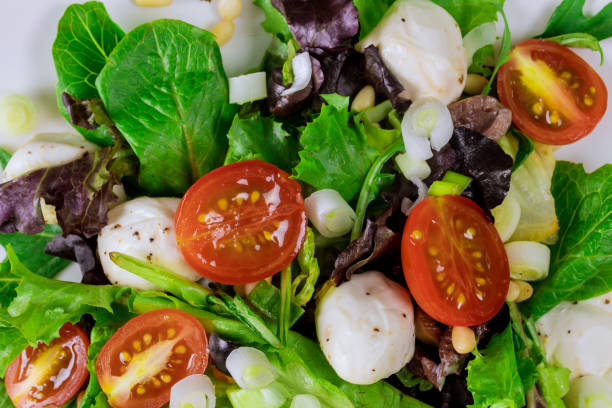 Spring Salad with cherry tomato, mozzarella and olive oil in a plate Spring salad with cherry tomato, mozzarella in a plate salad fruit lettuce spring stock pictures, royalty-free photos & images