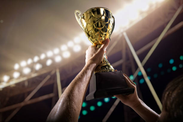 Athlete holding trophy cup above head in stadium Athlete holding trophy cup above head in stadium rivalry photos stock pictures, royalty-free photos & images
