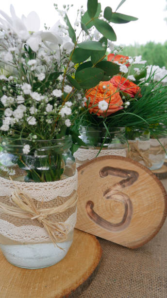 istock Table number three decorated with white daisy flowers and orange roses in jars 1159867385
