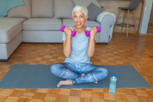 istock Fit mature woman lifting dumbbell while sitting at home 1159868071