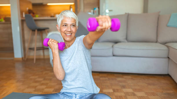 Staying fit is one way to age with grace Staying fit is one way to age with grace. Nice elderly woman taking pleasure in the workout. Active senior woman at home exercising with weights. Mature Woman Exercise At Home. senior bodybuilders stock pictures, royalty-free photos & images