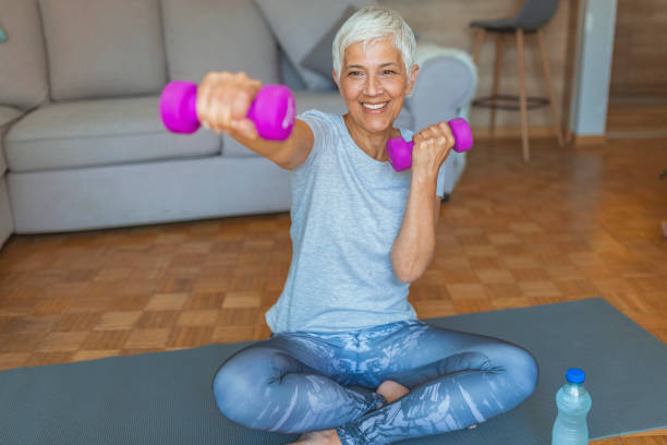istock Fit mature woman lifting dumbbell while sitting at home 1159869002