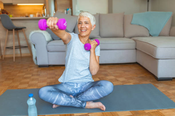 Staying fit is one way to age with grace Woman Exercising With Dumbbell At Home. Feeling great inside and out! Age is no excuse to slack on your health. Portrait of smiling senior woman holding dumbbell fitness ball photos stock pictures, royalty-free photos & images