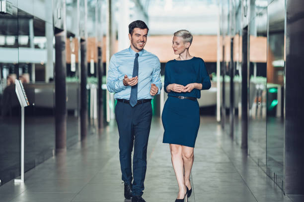 Private conversation outside the office Couple of business persons talking in the office building corridor woman necktie stock pictures, royalty-free photos & images