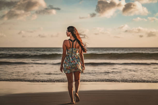 istock Woman walking alone on the beach in evening 1159874242