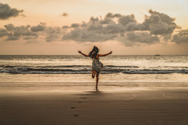 Never miss an opportunity to live life Happy woman running with arms up on the beach at sunset, Bali, Seminyak, Double six beach. Rear View Of A Woman Watching The Sunset At Seminyak Beach In Bali Indonesia. Asia travel series. Beautiful woman with dark hair running towards the sea in Balinese beach. Beautiful young woman with her arms up running on and enjoying the sense of freedom on a desolate beach. kuta beach stock pictures, royalty-free photos & images