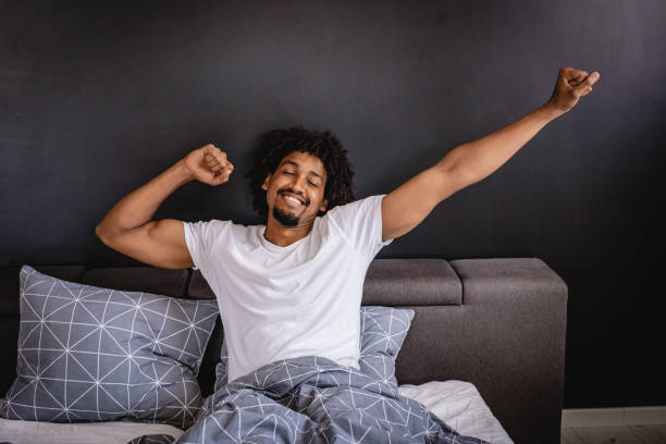 It's time to wake up the man is waking up in bed in the morning with a smile on his face bedtime photos stock pictures, royalty-free photos & images