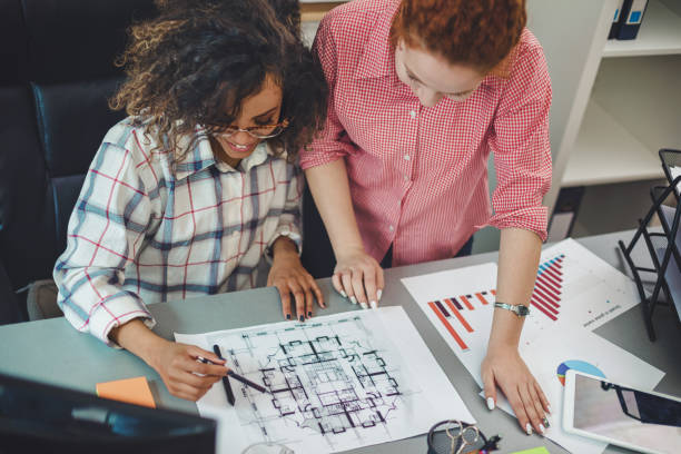 istock Two young female designer in office working on architects project together 1159881029