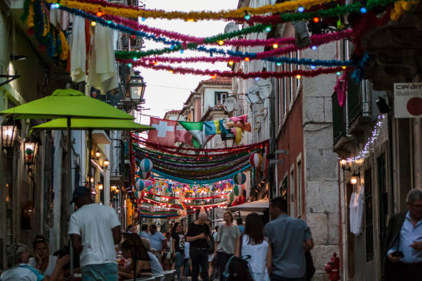 People in typical Lisbon neighborhood decorated for the popular saints Lisbon, Portugal - CIRCA June, 2019: Local and tourists in typical Lisbon neighborhood decorated for the popular saints arraial do cabo stock pictures, royalty-free photos & images