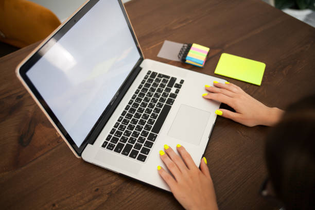 istock Women's hands with trend yellow manicure typing text on a laptop keyboard. 1159884851