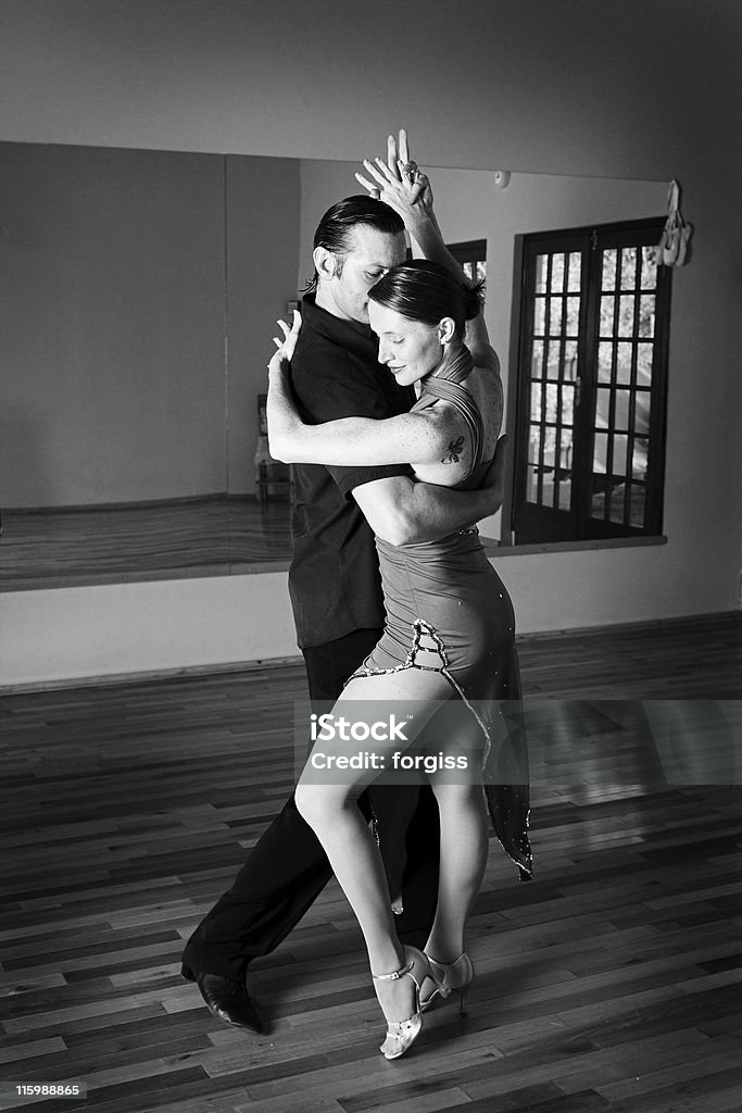 Two ballroom dancers practicing in their studio A young adult couple dancing and practicing ballroom dancing together in a studio - Focus on woman, Black and white - high key efect Tango - Dance Stock Photo